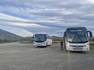 Zwei Reisebusse in einer offenen Landschaft.